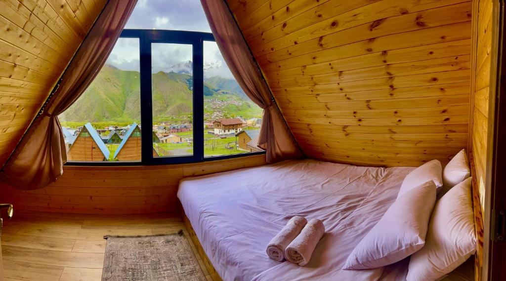 Bett in einem Zimmer mit einem großen Fenster in der Unterkunft Cozy Home Kazbegi in Kazbegi