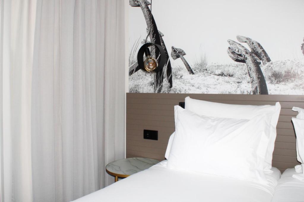 een slaapkamer met een bed met witte lakens en een raam bij AP Cabanas Beach & Nature - Adults Friendly in Cabanas de Tavira