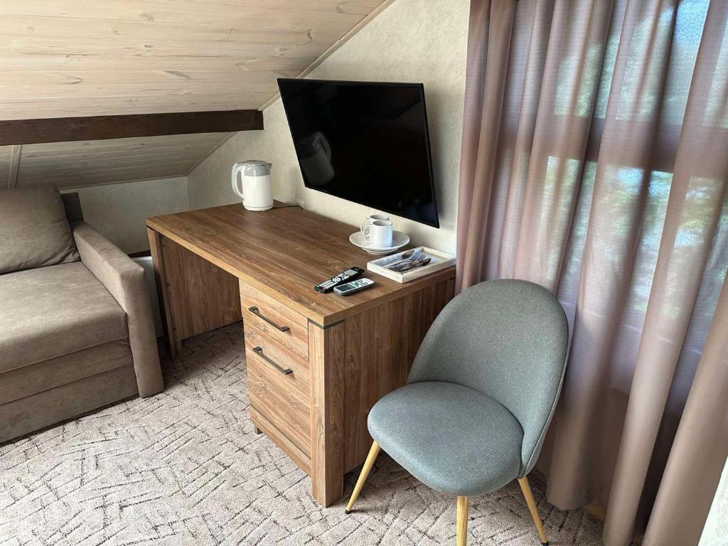 Zimmer mit einem TV, einem Stuhl und einem Schreibtisch. in der Unterkunft Mini Hotel on Brovarskaya in Kiew