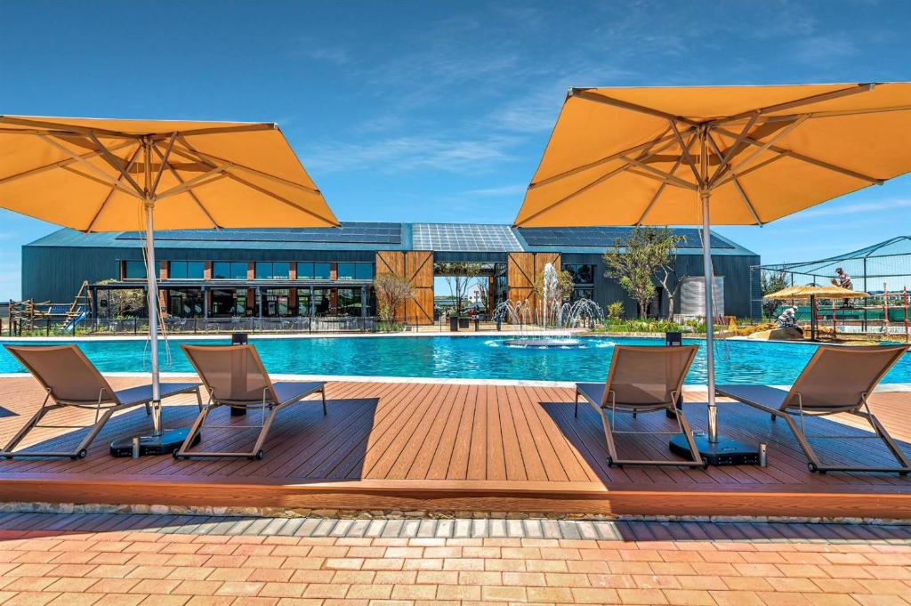 a pool with two chairs and two umbrellas at Crystal Lagoon Homes in Pretoria