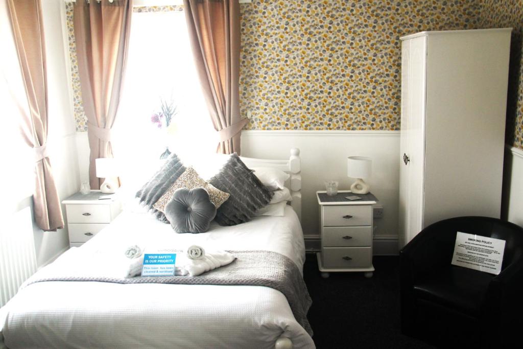 a bedroom with a large white bed with a window at Serena Court Hotel in Skegness
