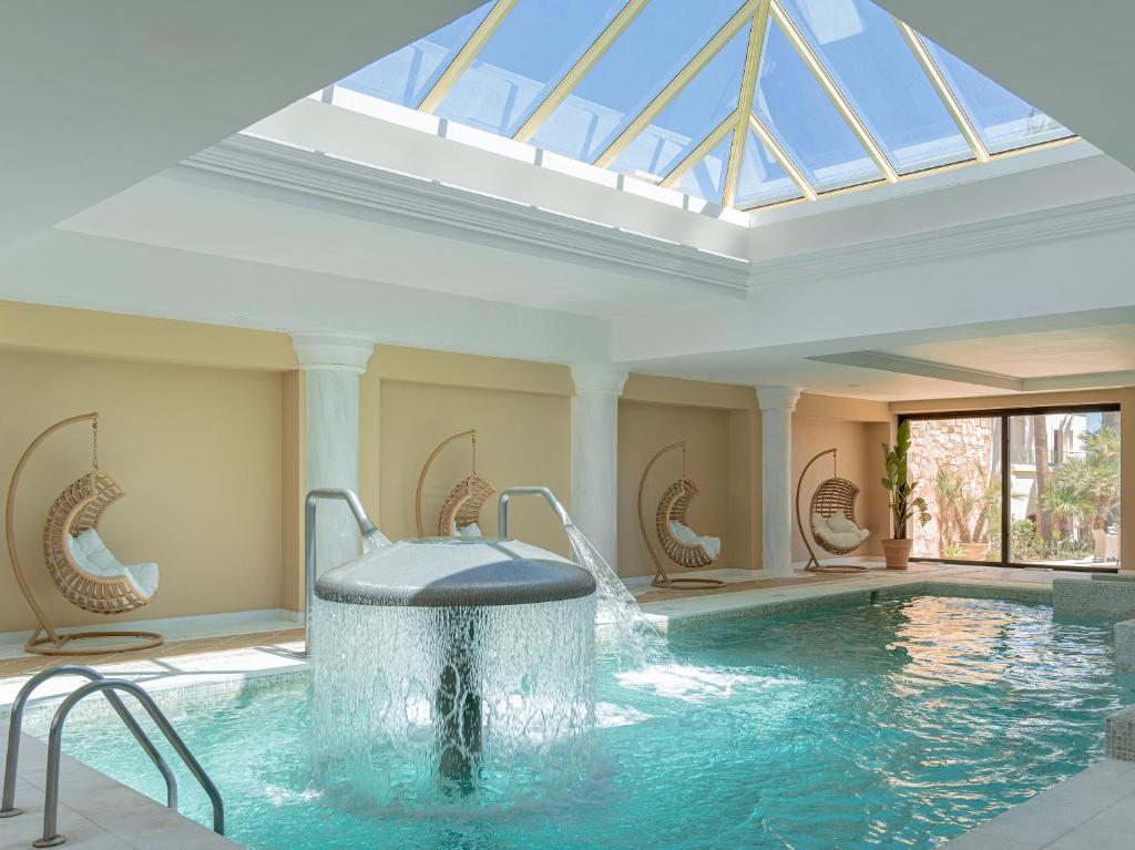a swimming pool with a water fountain in a building at Grecotel Marine Palace & Aqua Park in Panormos Rethymno