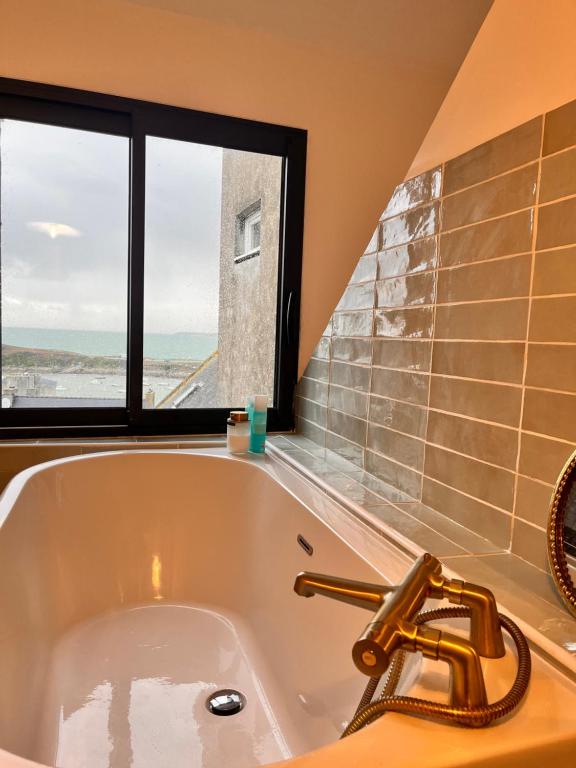 eine Badewanne im Bad mit Fenster in der Unterkunft Charmante chambre avec sa salle de bain, vue mer. in Le Conquet
