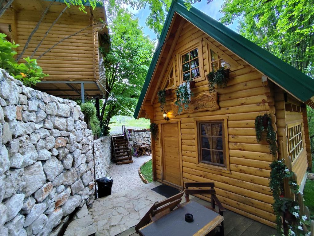 a log cabin with a stone wall and a patio at Brvnara Fairy Tale in Cetinje
