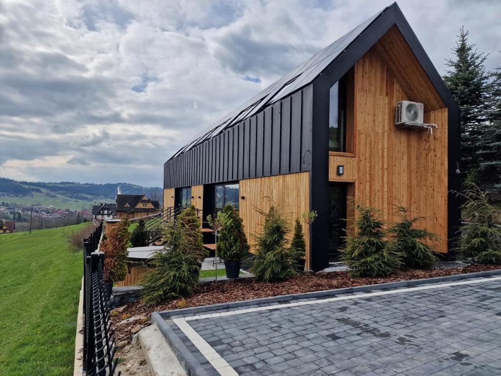 ein Holzhaus mit schwarzem Dach in der Unterkunft Bukowina Tatrzańska -Czarna Góra- Black Apart- piękny widok na Tatry in Bukowina Tatrzańska