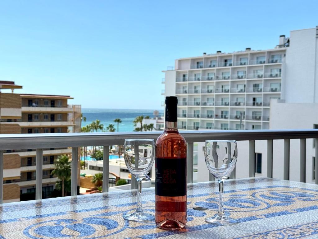 托雷莫利諾斯的住宿－La Carihuela a 150 metros de la playa con espectaculares vistas，一张桌子上摆放着一瓶葡萄酒和两杯酒杯