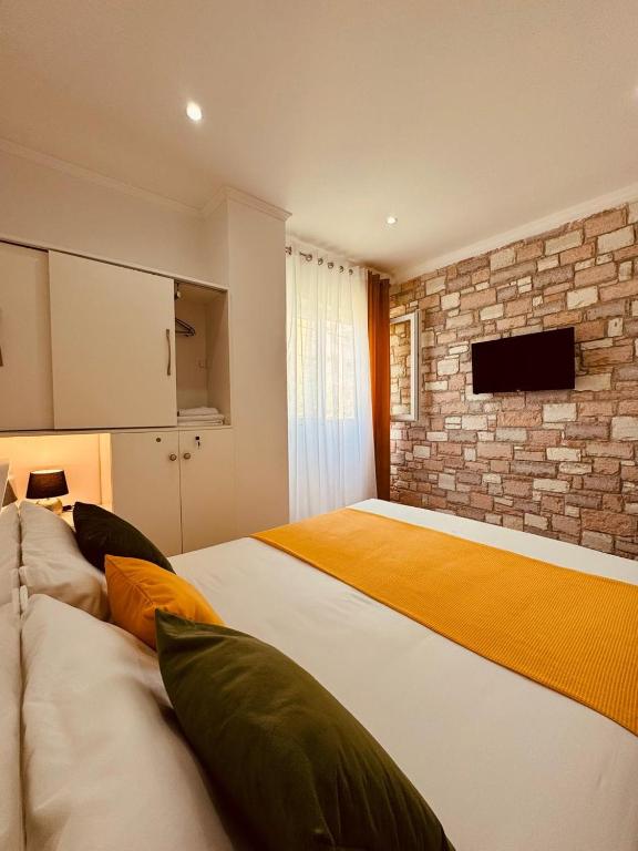 a bedroom with two beds and a brick wall at Orfeu apartments Ksamil in Ksamil