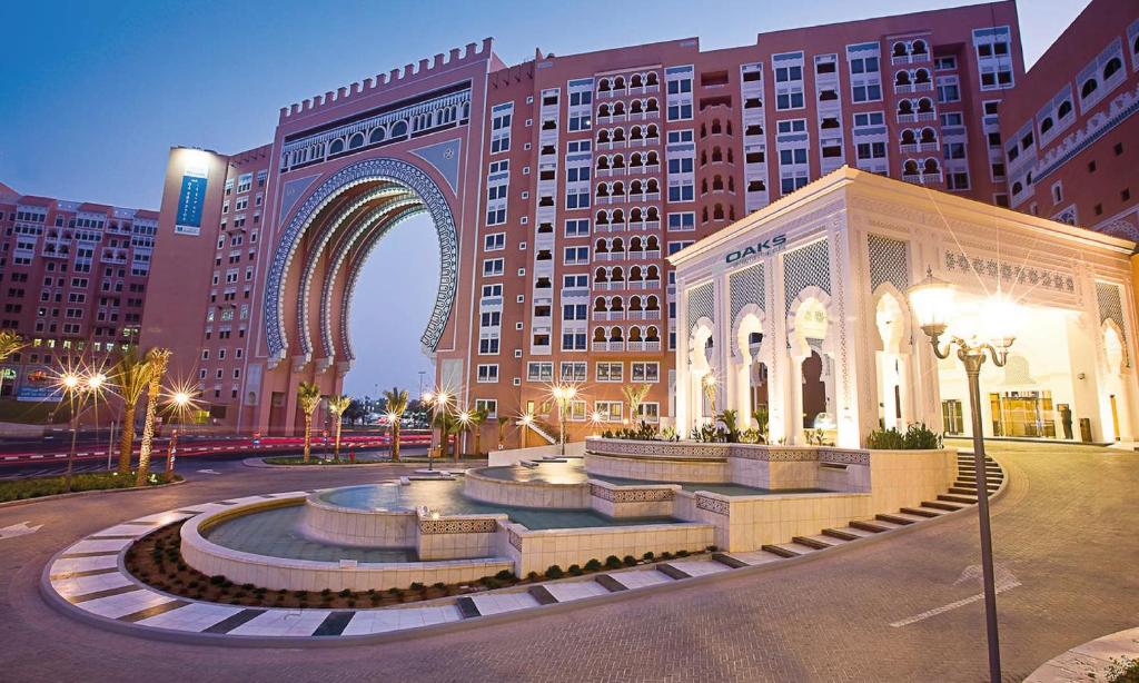 un grand bâtiment avec une fontaine au milieu d'une ville dans l'établissement Oaks Ibn Battuta Gate Dubai, à Dubaï