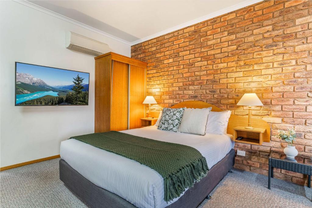 a bedroom with a bed and a brick wall at BIG4 Tasman Holiday Parks - Warrnambool in Warrnambool