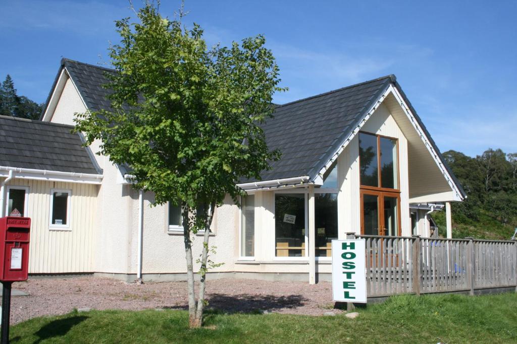 une maison avec un panneau devant elle dans l'établissement BCC Loch Ness Hostel, à Bearnock