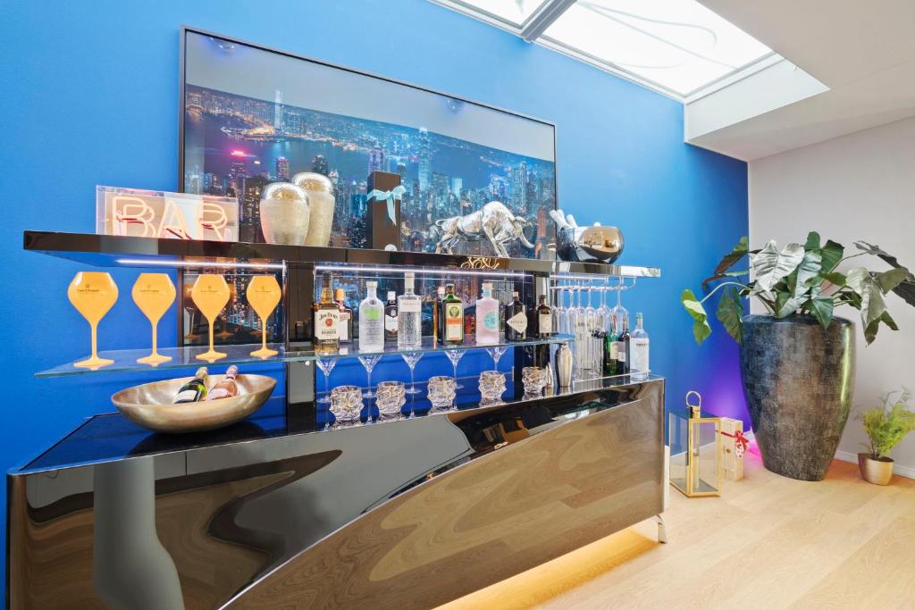 a bar with a blue wall with bottles and glasses at Exclusive spacious Apt. with garden in Zurich in Zürich