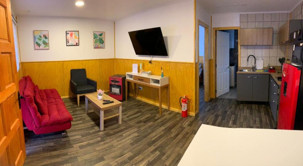 uma sala de estar com uma cadeira vermelha e uma televisão em Radio Navarino em Puerto Williams