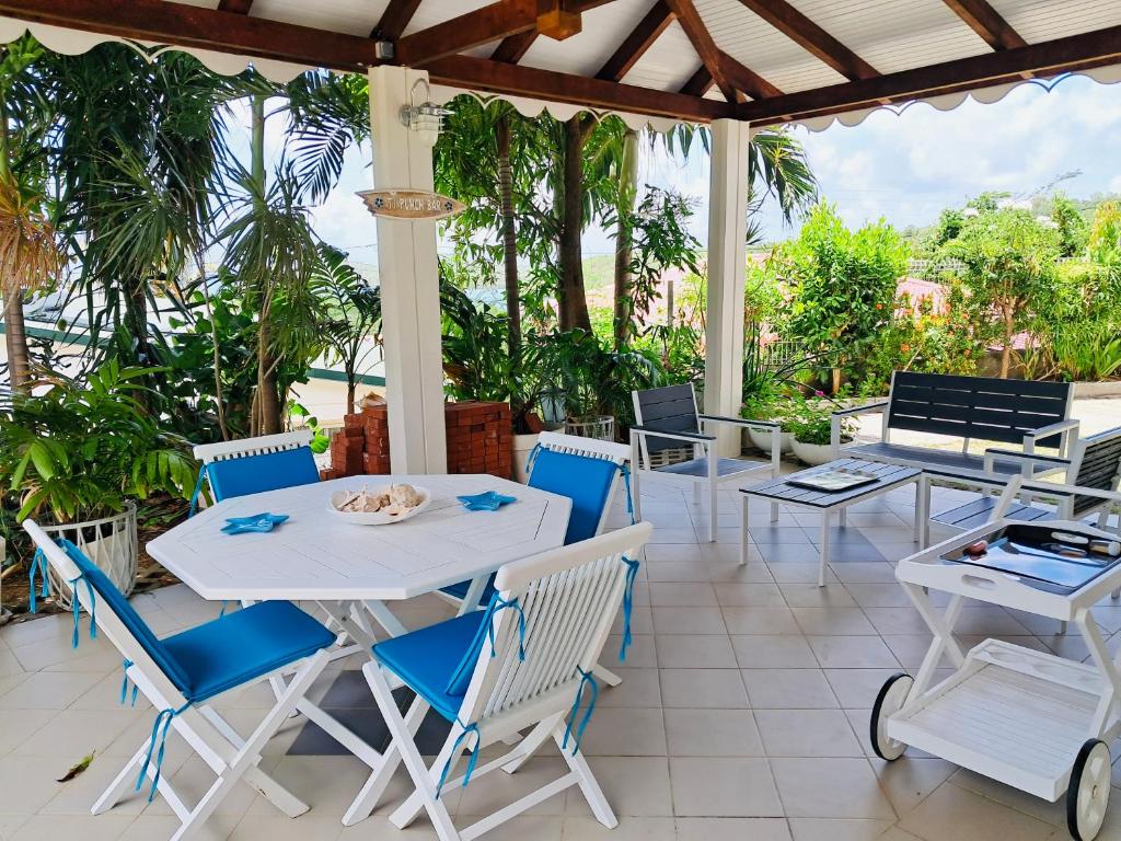 een patio met witte tafels en stoelen en palmbomen bij Maison Baie des Mulets in Le Vauclin