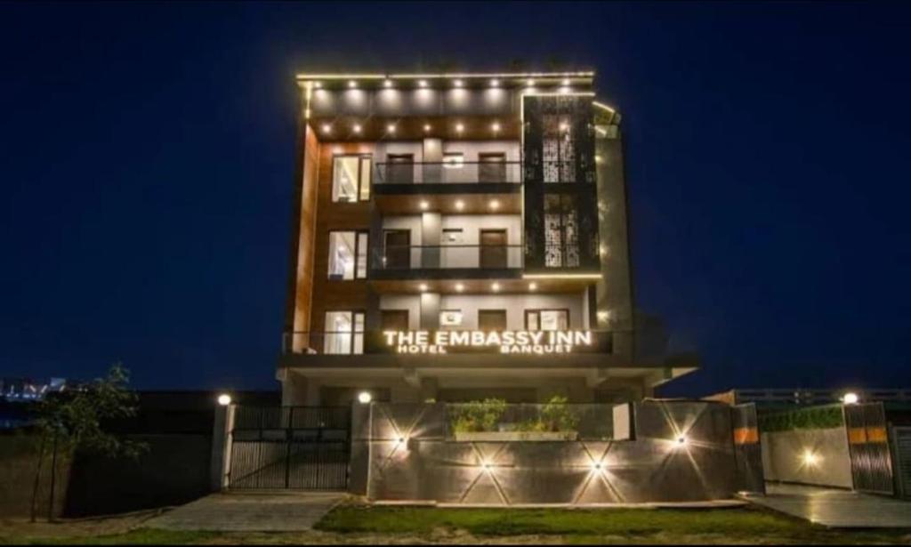 Un grand bâtiment avec des lumières allumées la nuit dans l'établissement The Embassy Inn, à Noida