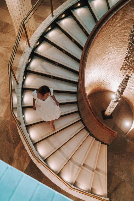 a woman is standing on a spiral staircase at Cádiz Bahía by QHotels in Cádiz