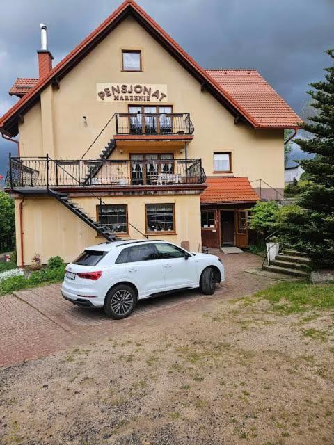a white car parked in front of a building at Pensjonat Marzenie in Przesieka