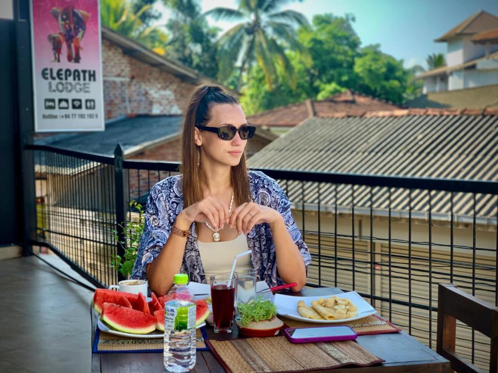 Una donna seduta a un tavolo con un piatto di cibo di Elepath Lodge- Pinnawala a Pinnawala