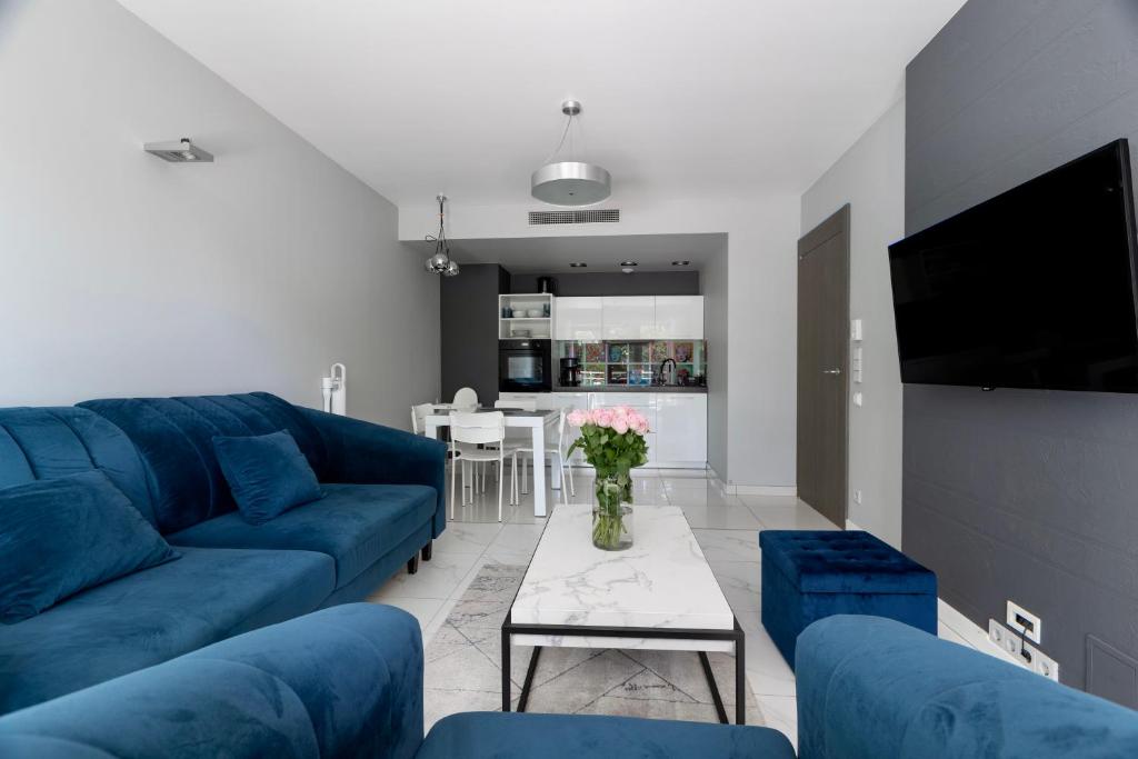 - un salon avec un canapé bleu et une table dans l'établissement Apartament 208, à Międzyzdroje
