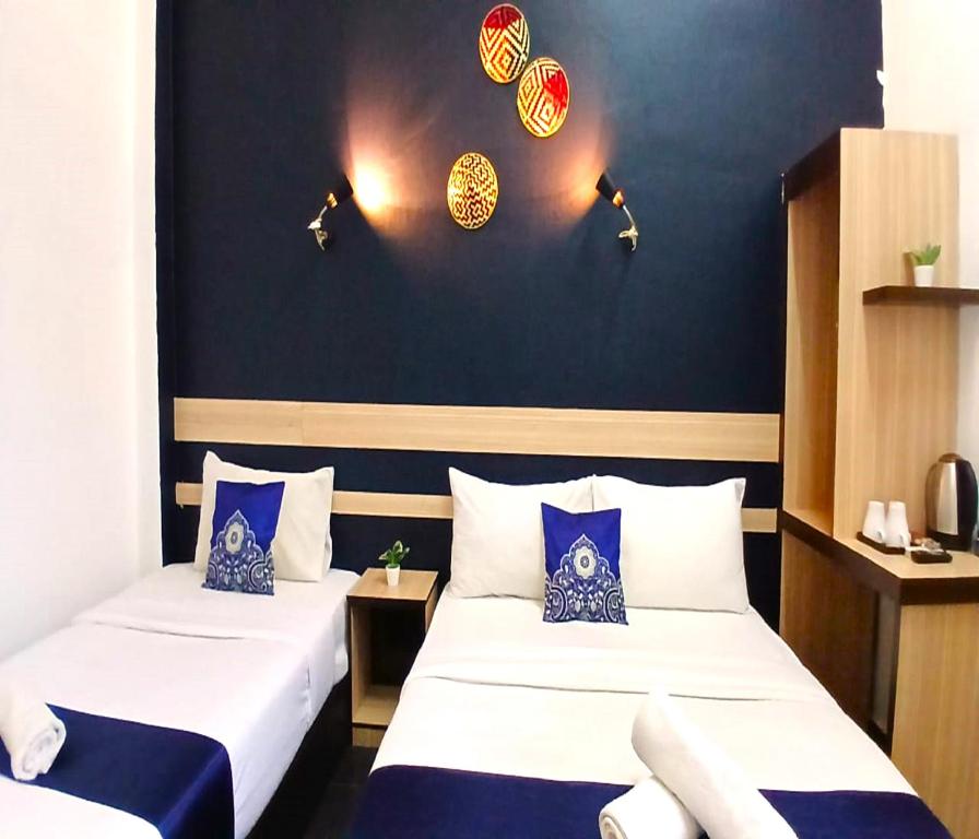 two beds in a room with blue walls at Alia Express Green Mango, Kota Bharu in Kota Bharu