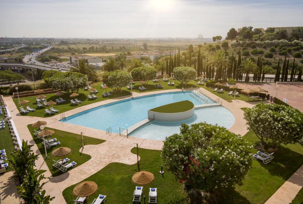 einen Blick über einen Pool in einem Park in der Unterkunft Ilunion Alcora Sevilla in San Juan de Aznalfarache