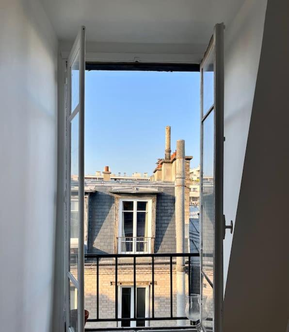 - une vue sur le bâtiment depuis une fenêtre ouverte dans l'établissement Charmante petite chambre vue sur les toits de Paris avec ascenseur - quartier animé et proche des jeux olympiques, à Paris