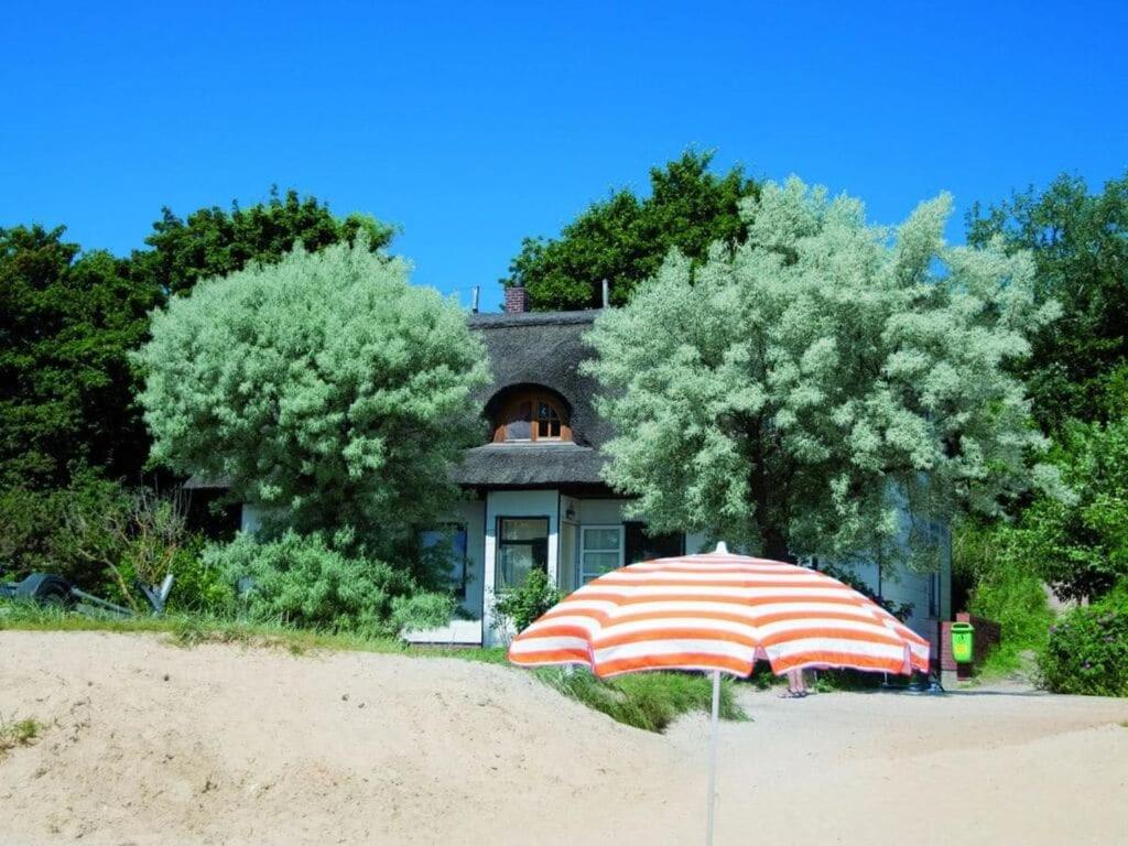 an umbrella sitting on the beach in front of a house at on the beach no 991 in Wulfen auf Fehmarn