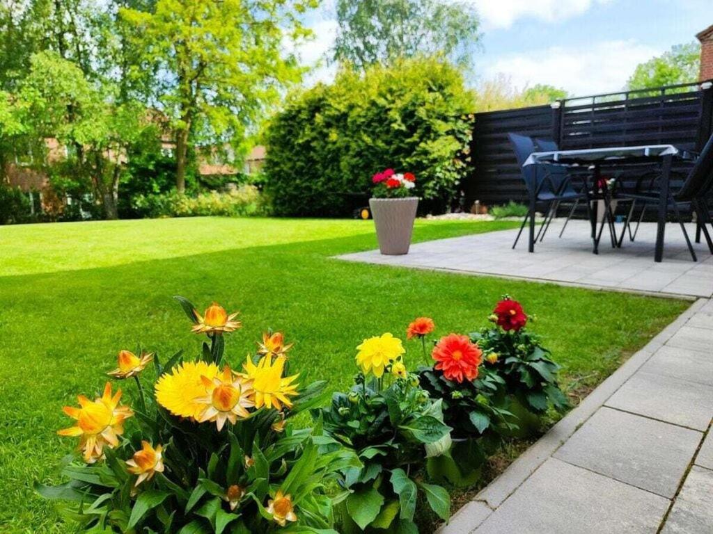 a garden with a table and flowers in the grass at Holiday home Heide Comfortable holiday residence in Bad Fallingbostel
