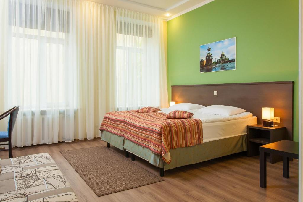Classiky Mini Hotel في سانت بطرسبرغ: غرفة نوم بسرير كبير في غرفة خضراء