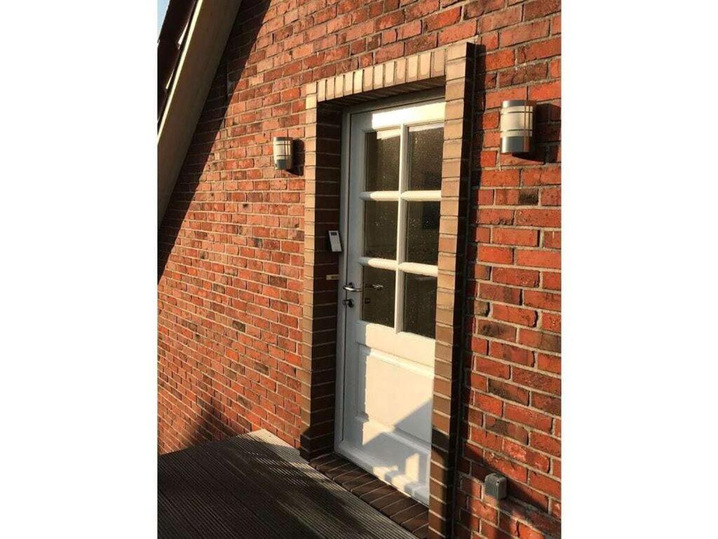 a door in a brick building with a window at Haus Butje Comfortable holiday residence in Fedderwarderdeich