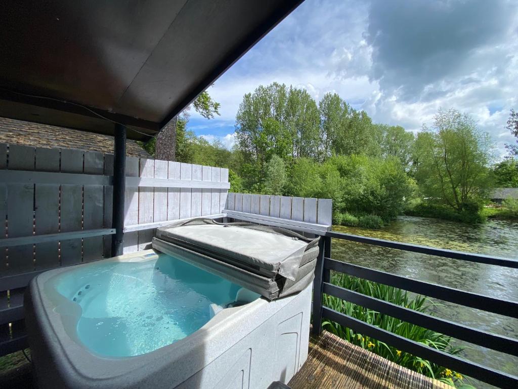 uma banheira de hidromassagem numa varanda com vista para um rio em Magpie 1 Hot Tub HuntersMoon-Warminster-Bath-Wiltshire em Warminster