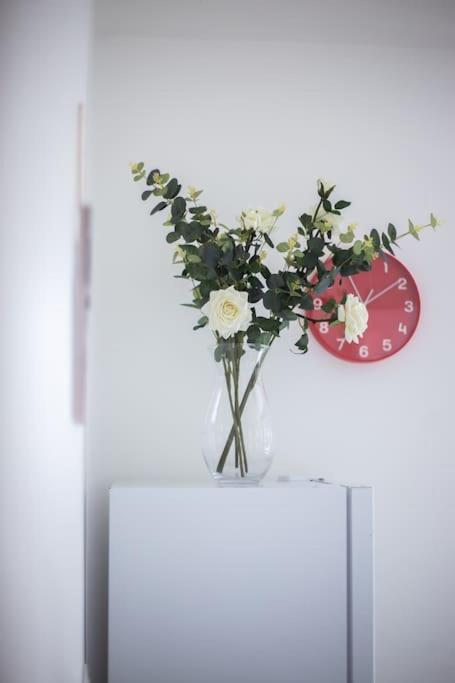 a vase of flowers on a table with a clock at Coastal Haven in Leigh-on-Sea in Southend-on-Sea