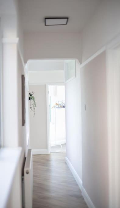 a hallway with white walls and wooden floors and a stairway at Coastal Haven in Leigh-on-Sea in Southend-on-Sea