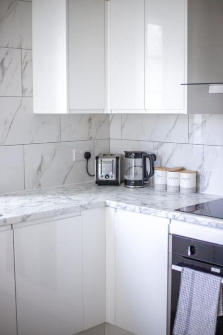 a kitchen with white cabinets and a counter with a toaster at Coastal Haven in Leigh-on-Sea in Southend-on-Sea