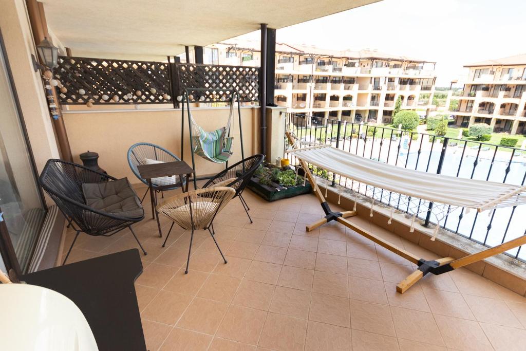 einen Balkon mit Stühlen und einer Hängematte auf einem Gebäude in der Unterkunft Apartment Omnia in Kaliakria Resort in Topola