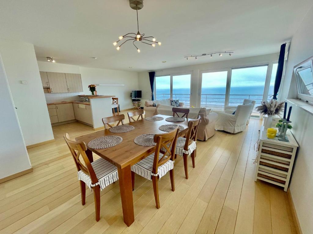 a dining room and living room with a table and chairs at 3BR Zeedijk apartment Ocean View in Blankenberge