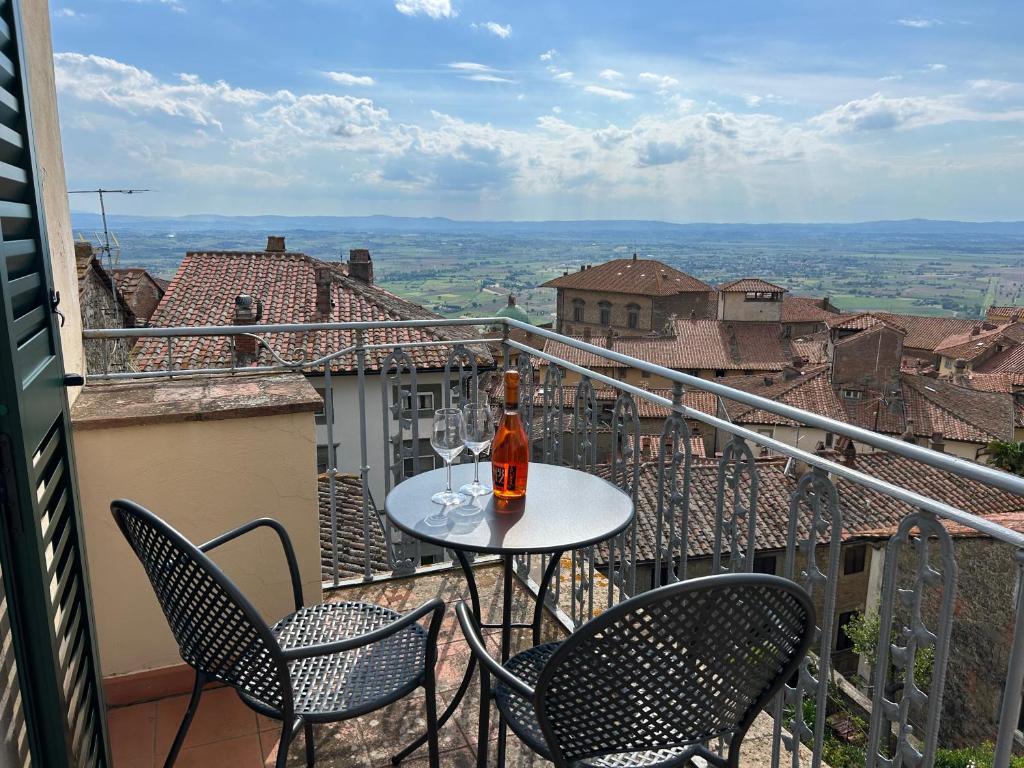 a table and chairs on a balcony with a bottle of wine at Cortona's Rooftop Nest in Cortona