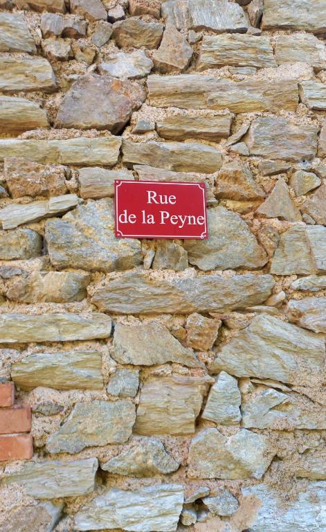 a red sign on the side of a stone wall at L&#39;Armandière, maison de caractère où règne calme et sérénité. in Pézenes-les-Mines
