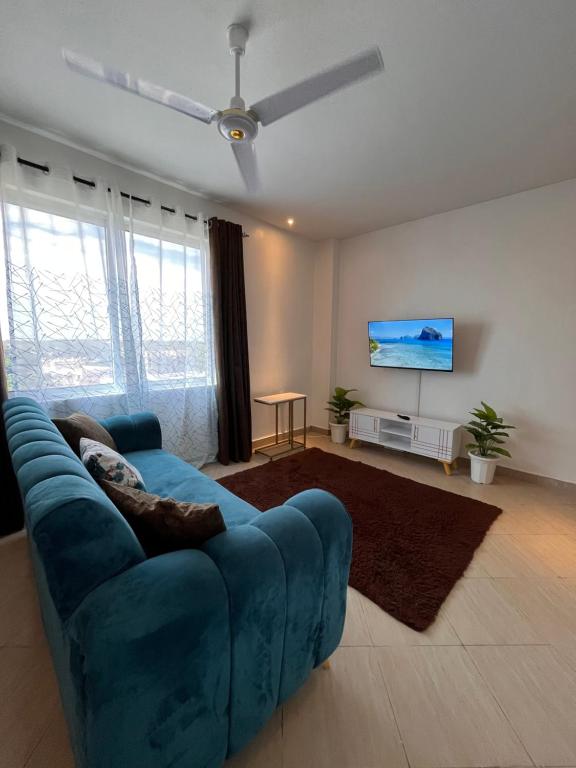 a living room with a blue couch and a flat screen tv at Haller Park Apartments Pacific Bamburi in Mombasa