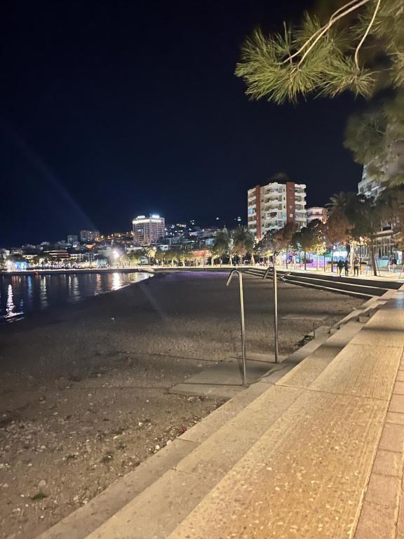 a beach at night with a city in the background at Electra The Seaside Apartments in Sarandë