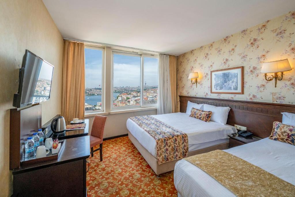 a hotel room with two beds and a television at Pera Rose Hotel - Taksim Pera in Istanbul
