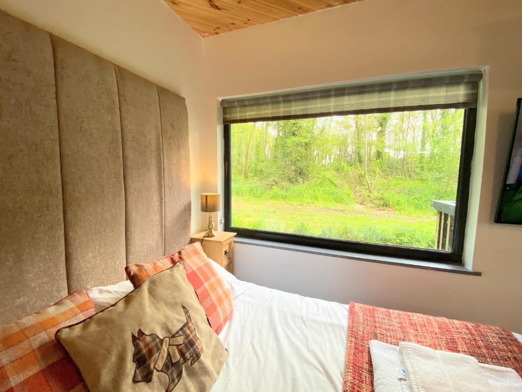 een slaapkamer met een bed en een groot raam bij Arc Pod-HotTub-HuntersMoon-Warminster-Bath in Warminster