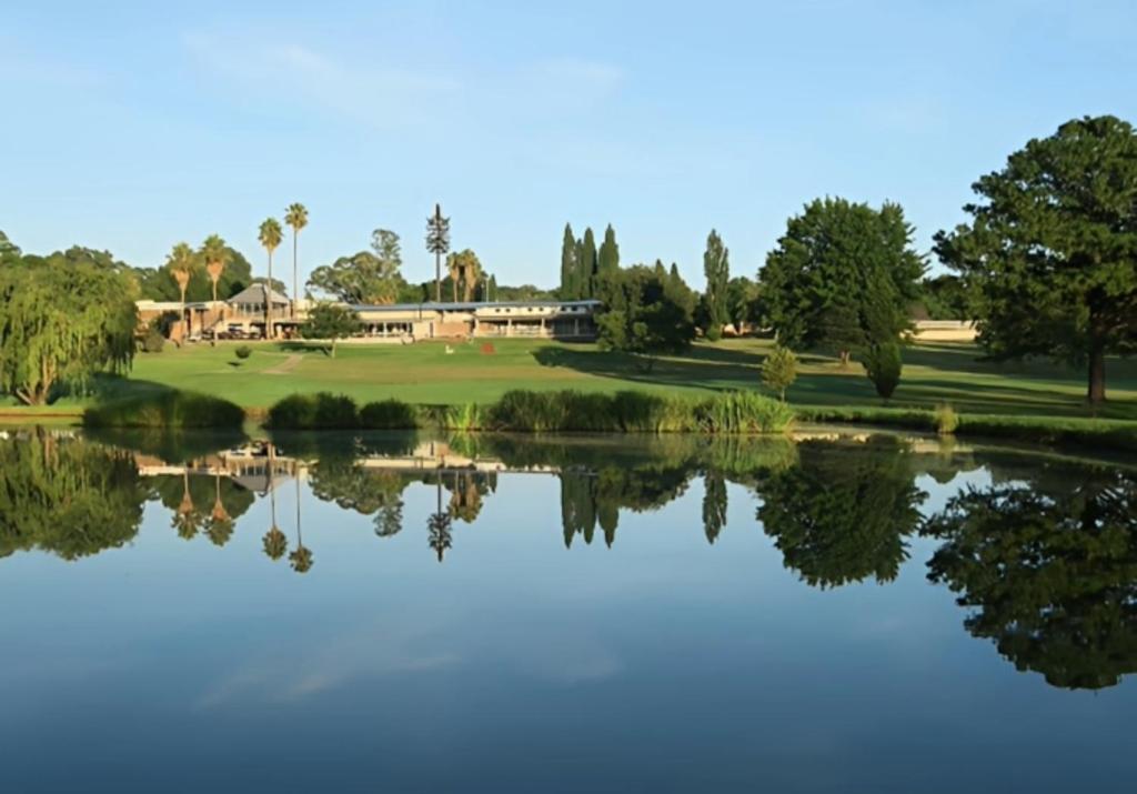 Una vista de un campo de golf desde el otro lado de un lago. en Middelburg Country Club, en Middelburg