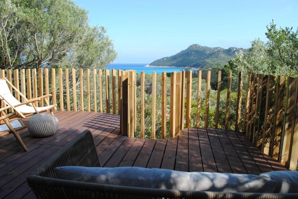 a wooden deck with a chair and a fence at Cala Sinzias beach house with stunning views in Costa Rei