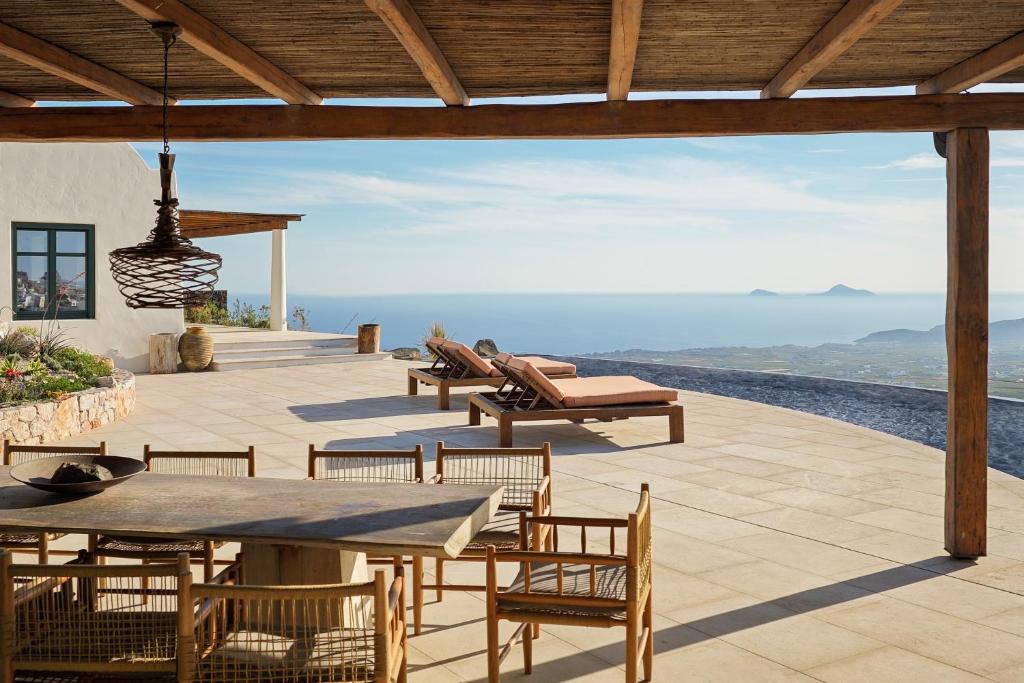 d'une terrasse avec une table et des chaises et une vue. dans l'établissement Patina Vivera Estate Santorini, à Pyrgos