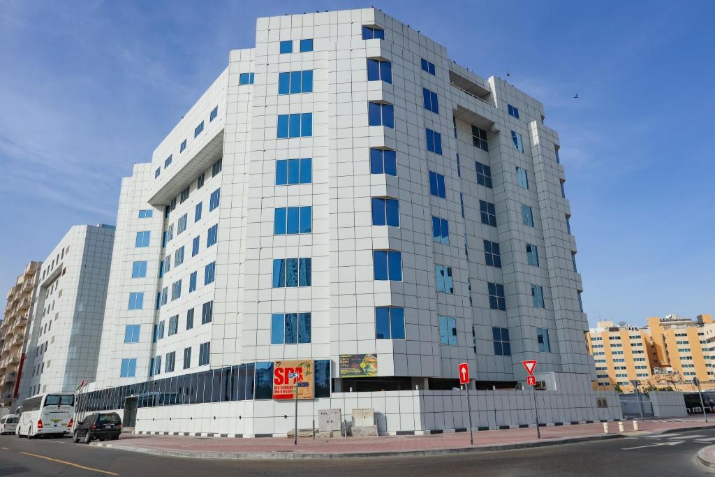 un grand bâtiment blanc avec des fenêtres bleues sur une rue dans l'établissement Omega Hotel Dubai, à Dubaï