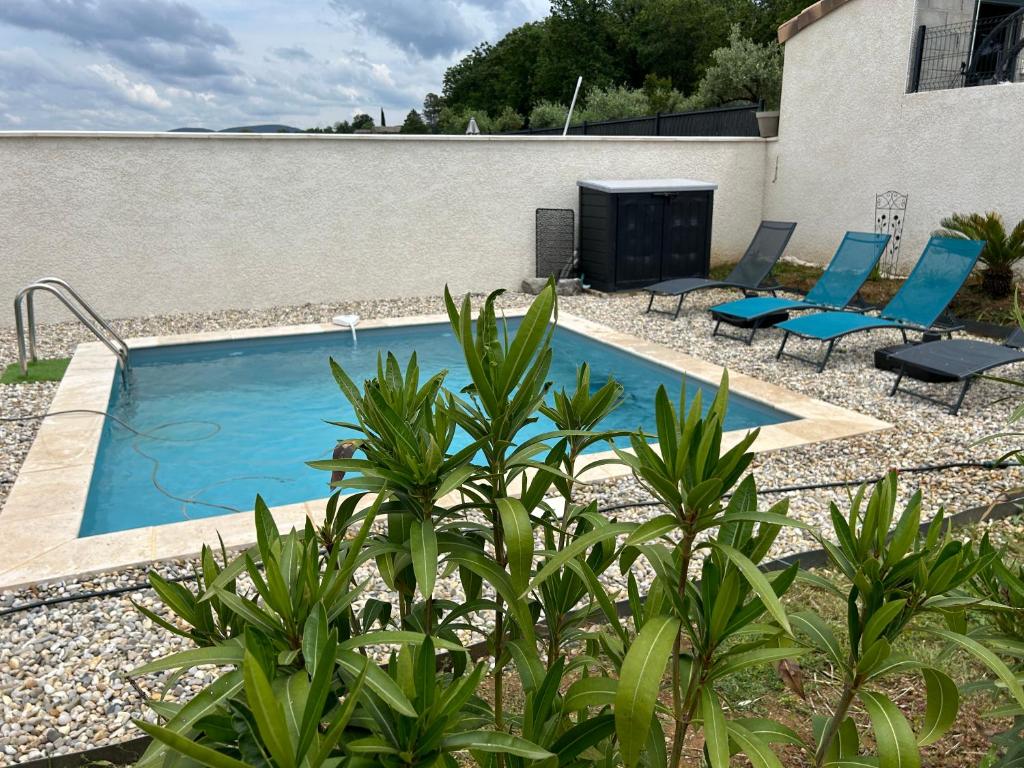 una piscina con sedie blu accanto a un edificio di Vacances en Ardèche "maison pont d'arc" a Vallon-Pont-dʼArc