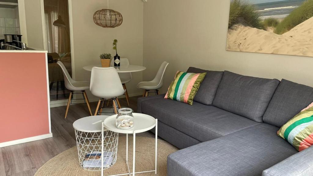 een woonkamer met een grijze bank en een tafel bij Appartement De Jutter, Resort Amelander Kaap in Hollum