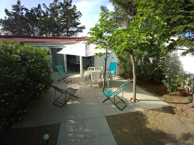patio con sedie, tavolo e ombrellone di Maison Jardin Wifi - Climatisation - 100 m plage sauvage - 20 min Perpignan a Torreilles