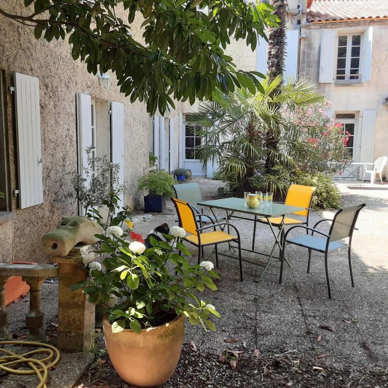 un patio avec une table, des chaises et des plantes dans l'établissement Annexe du pont de la Charente, à Châteauneuf-sur-Charente