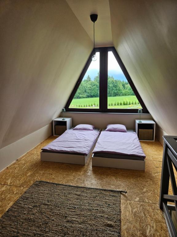 two beds in a room with a large window at PrzyTuLasek - domek pod lasem, blisko Energylandii in Zator